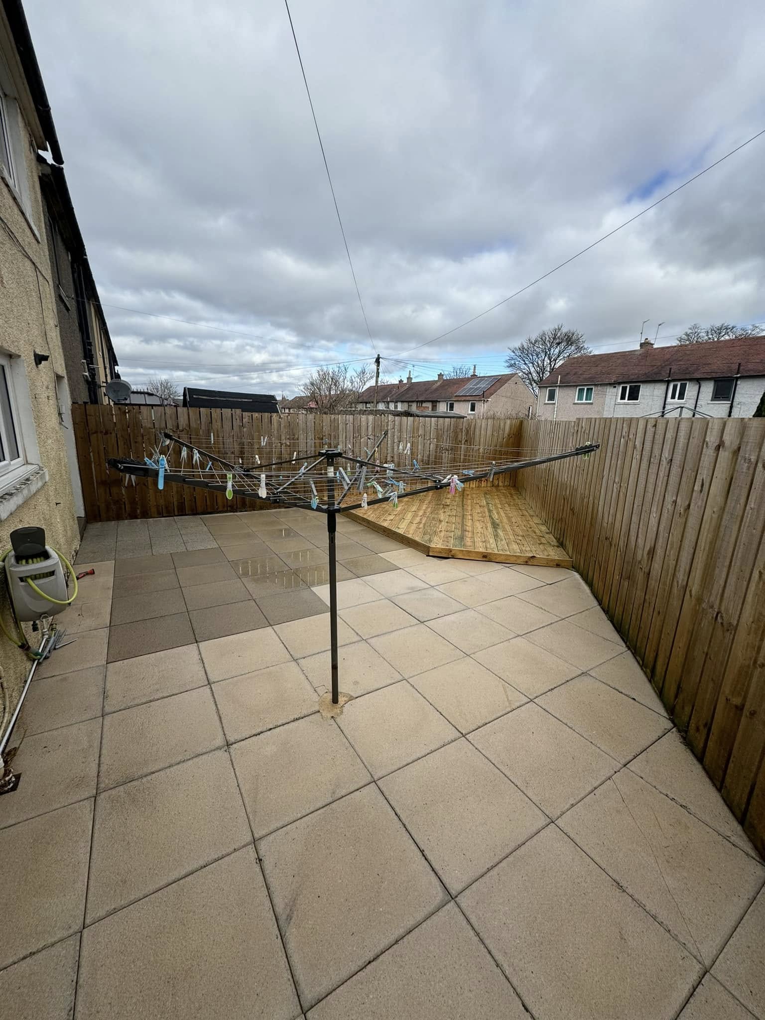Freshly cleaned grey paving-slab patio with new timber decking