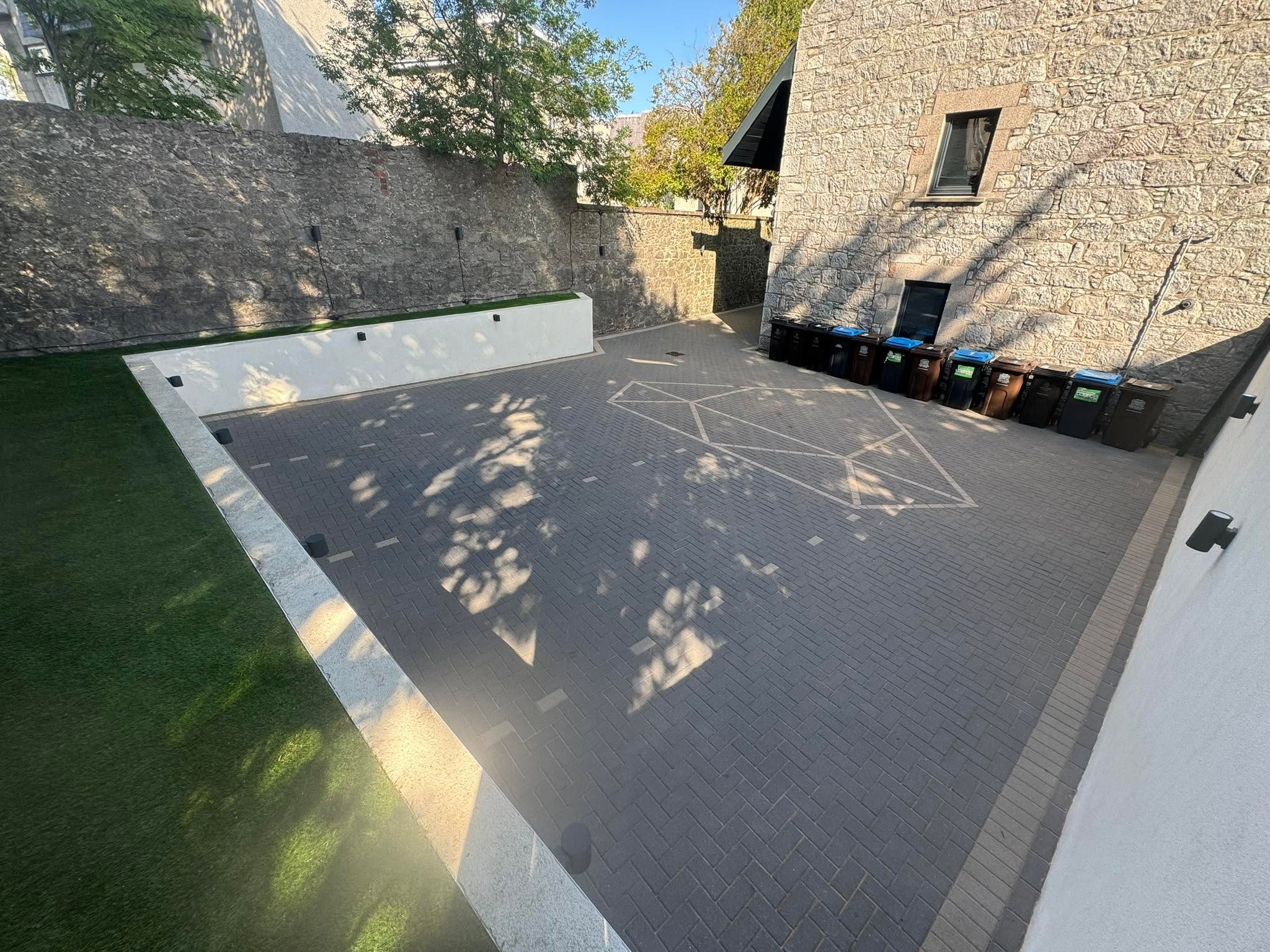 Cleaned block-paved courtyard and bin store, granite walls